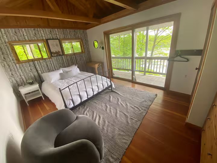 Bedroom with birch wallpaper and sliding door to lake-view deck