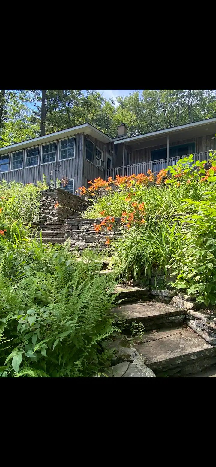 Cabin exterior with stone steps and daylilies in summer