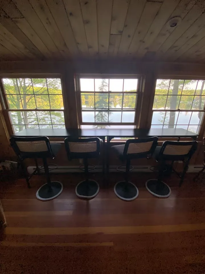 Window bar with four stools overlooking Shehawken Lake — typical 5pm spot at the cabin after a day exploring Wayne County