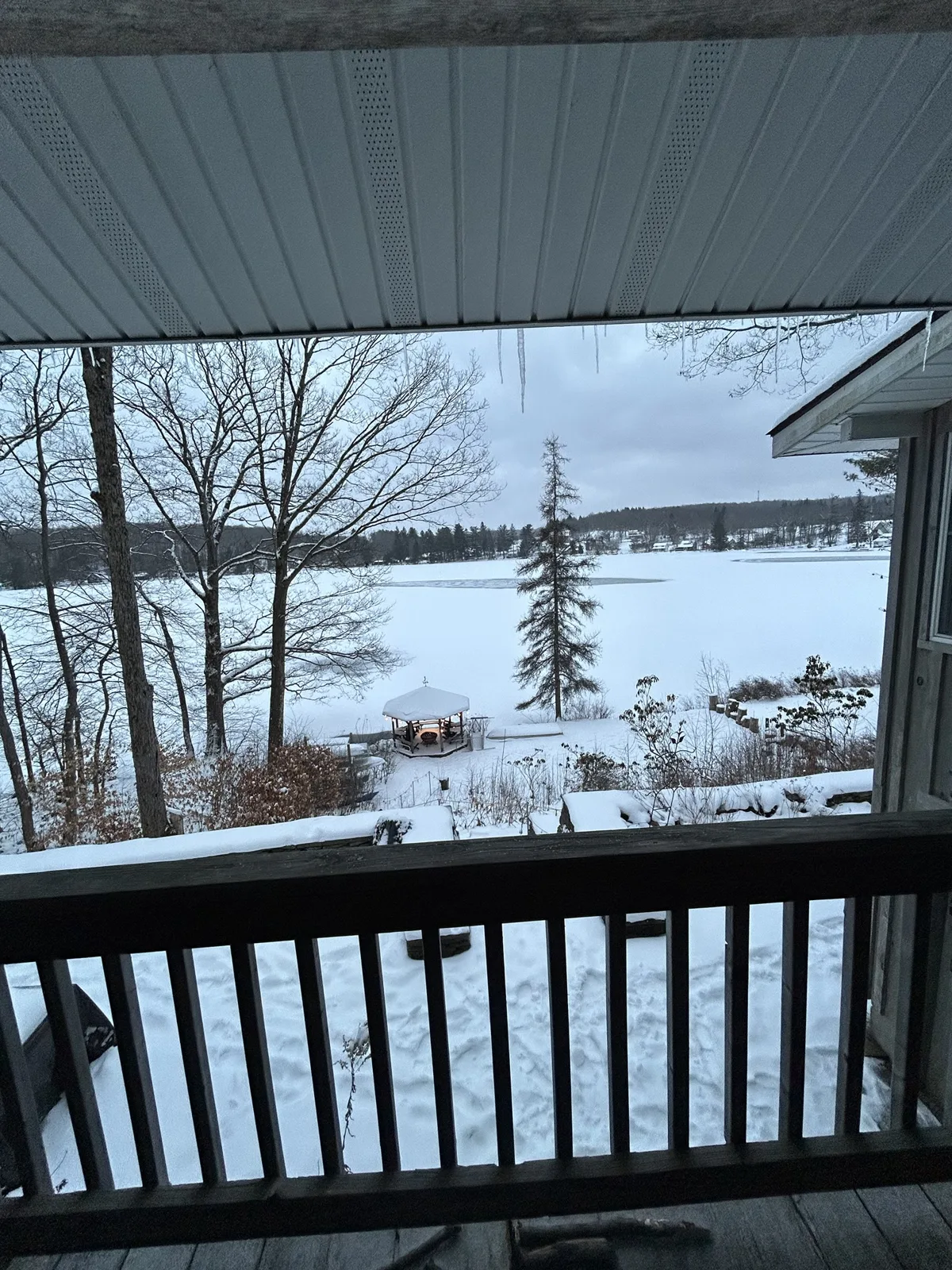 View from the snowy deck at Shehawken Lake Cabin over the frozen lake, with the gazebo lit up below